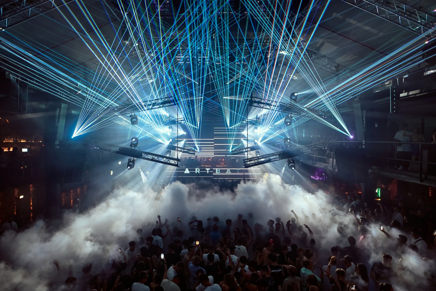 Resistance event with blue and green lasers cutting through fog over a packed crowd